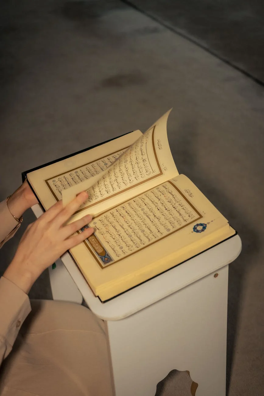 Close-up of hands holding an open Quran, symbolizing devotion in prayer.