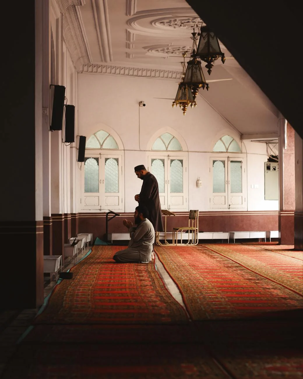 Two men engage in prayer inside a mosque in Peshawar, showcasing Islamic architecture and reverence.