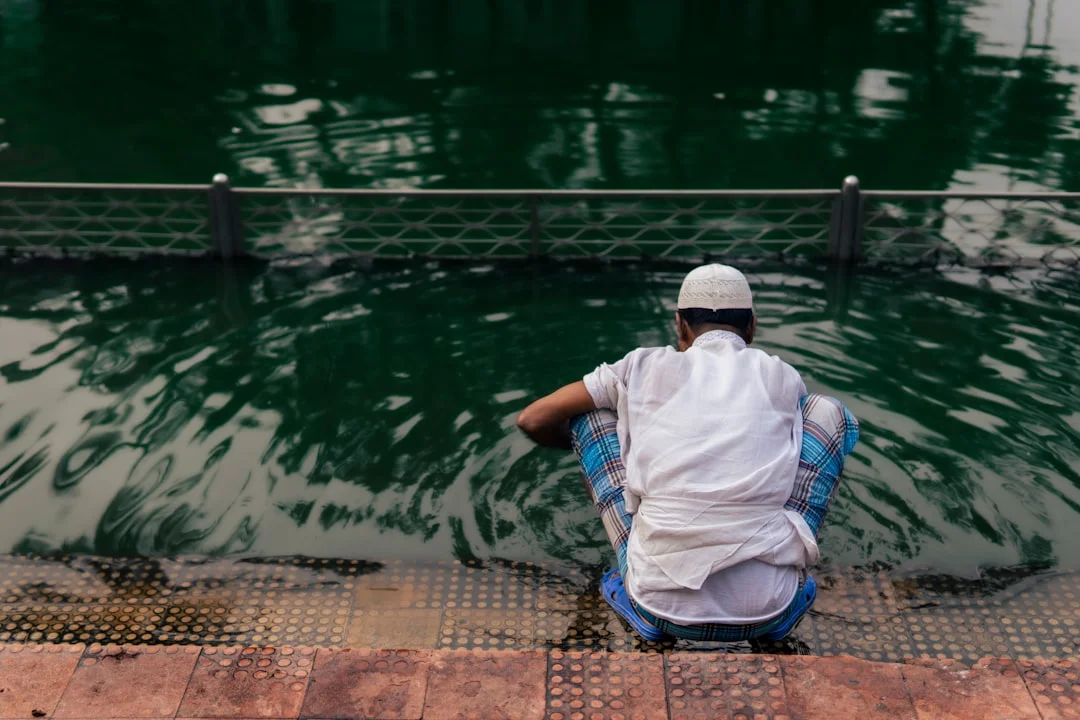 a person sitting on a bench in front of a body of water
